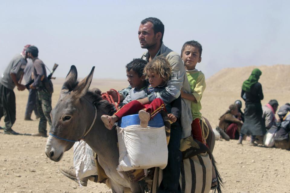 Displaced people from minority Yazidi sect, fleeing violence from forces loyal to Islamic State in Sinjar town, ride donkey as they make way towards the Syrian border, on outskirts of Sinjar mountain