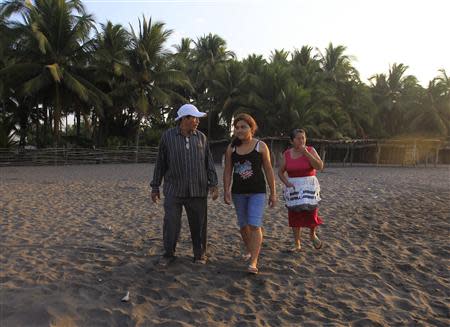 The family of castaway fisherman Jose Salvador Alvarenga -- (L-R) his father Jose Ricardo, sister Fatima Orellana and mother Maria Julia Alvarenga -- walk along a stretch of beach in their fishing hometown of Ahuchapan February 4, 2014. REUTERS/ Ulises Rodriguez