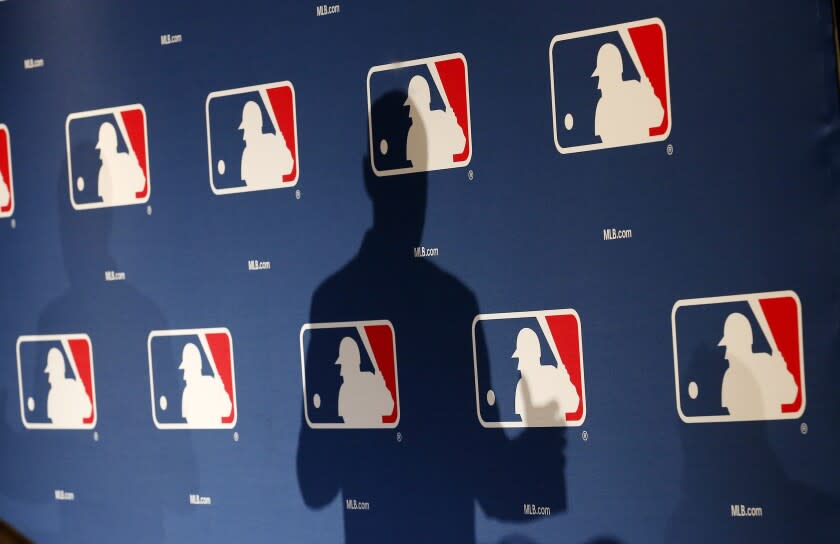 FILE - In this Monday, Feb. 23, 2015 file photo, the shadow of MLB Commissioner Rob Manfred is projected on an MLB logo backdrop in Phoenix. Major league teams steeply increased the money spent on young players in 2015, but the overall percentage of revenue devoted to players has remained relatively stable for a decade. (AP Photo/Ross D. Franklin)