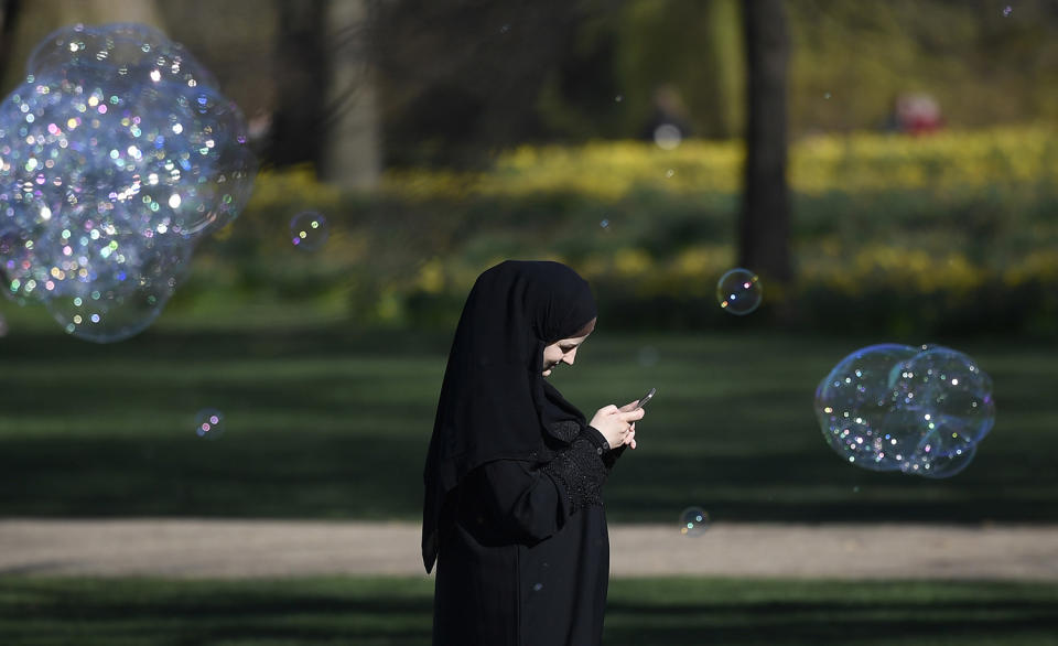 A woman walks past soap bubbles in St. James\’s Park in London