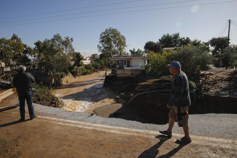 People inspect a damaged road after storms in Kineta village, about 68 kilometers (42 miles) west of Athens, Monday, Nov. 25, 2019. Authorities in Greece say two people have died and hundreds of homes have been flooded following an overnight storm that affected areas west of Athens. (AP Photo/Petros Giannakouris)