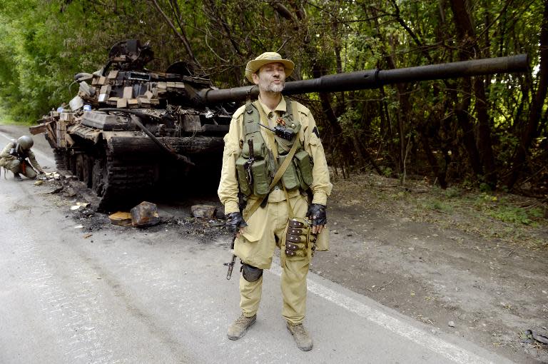A pro-Russia militant stands guard next to a Ukrainian tank destroyed by separatists in the eastern Ukrainian city of Donetsk on July 22, 2014