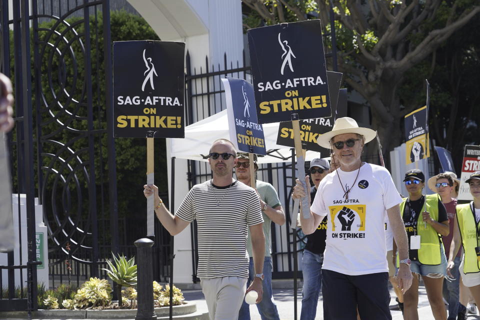 Aaron Paul, left, and Bryan Cranston, fellow cast members of the television series "Breaking Bad," walk on a picket line outside Sony Pictures studios on Tuesday, Aug. 29, 2023, in Culver City, Calif. The film and television industries remain paralyzed by Hollywood's dual actors and screenwriters strikes. (AP Photo/Chris Pizzello)