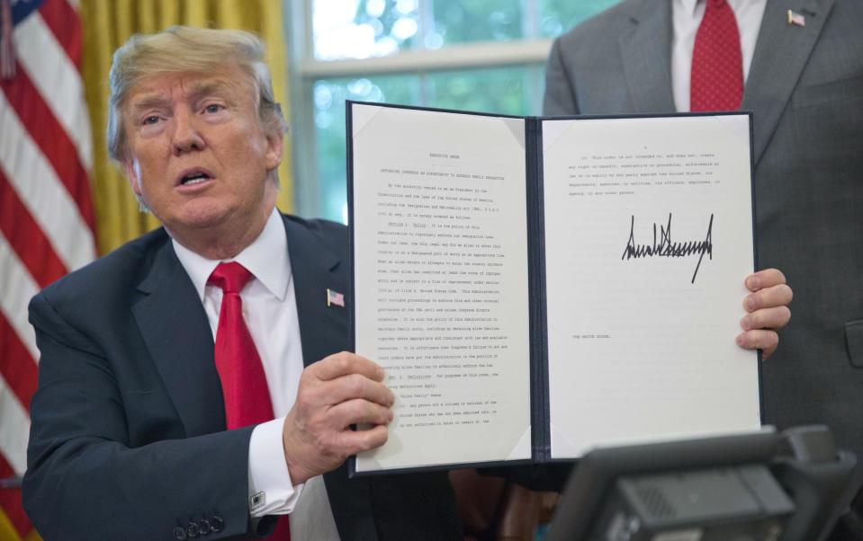 President Donald Trump holds up the executive order he signed to end family separations, during an event in the Oval Office: AP