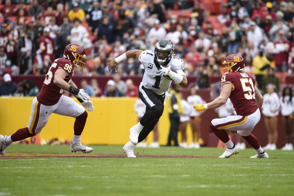 Philadelphia Eagles quarterback Jalen Hurts (1) runs with the ball against Washington Football Team defensive end Casey Toohill (95) and outside linebacker David Mayo (51) during the first half of an NFL football game, Sunday, Jan. 2, 2022, in Landover, Md. (AP Photo/Mark Tenally)