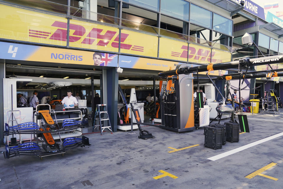 Technicians work around equipment and car parts in the The McLaren team pit at the Australian Formula One Grand Prix in Melbourne, Thursday, March 12, 2020. McLaren says it has withdrawn from the season-opening Australian Grand Prix in Melbourne after a team member tested positive for the coronavirus. (Michael Dodge/AAP Image via AP)
