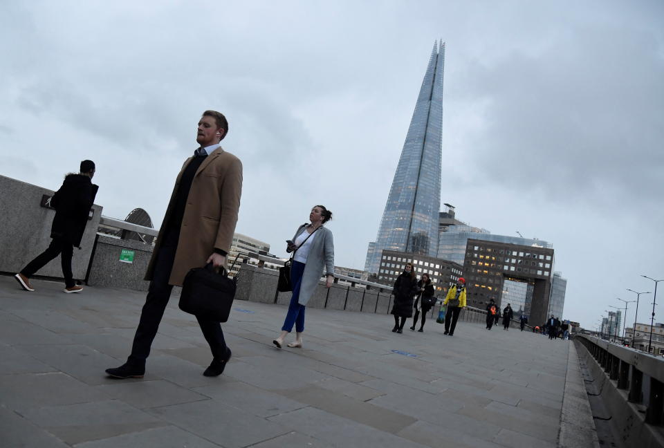 UK Workers cross London Bridge, with The Shard skyscraper seen behind, during the morning rush-hour, as the coronavirus disease (COVID-19) lockdown guidelines imposed by British government encourage working from home, in the City of London financial district, London, Britain, January 4, 2022. REUTERS/Toby Melville
