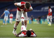 Arsenal's Kieran Tierney helps teammate Ainsley Maitland-Niles with cramp during the FA Cup semifinal soccer match between Arsenal and Manchester City at Wembley in London, England, Saturday, July 18, 2020. (AP Photo/Matt Childs,Pool)