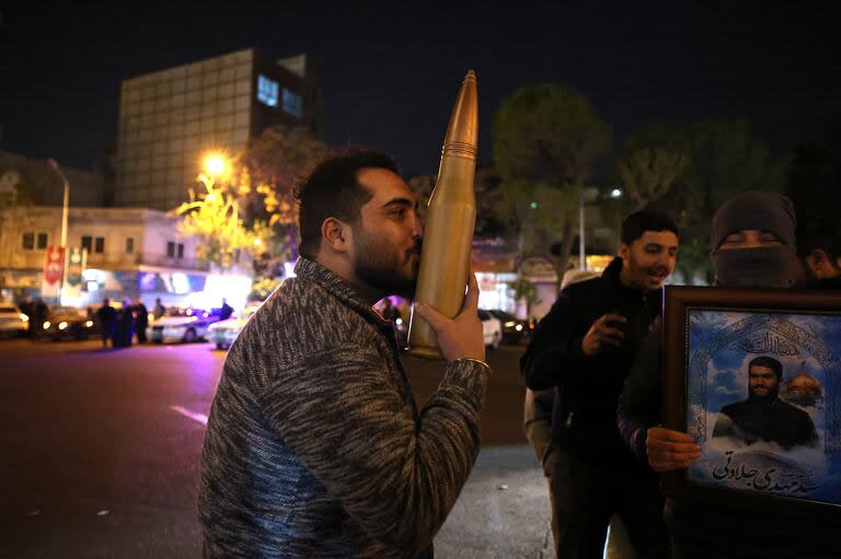 A demonstrator kisses a bullet shell replica as others gather at Palestine Square in Tehran on April 14, 2024, after Iran launched a drone and missile attack on Israel. Iran's Revolutionary Guards confirmed early April 14, 2024 that a drone and missile attack was under way against Israel in retaliation for a deadly April 1 drone strike on its Damascus consulate. (Photo by ATTA KENARE / AFP)