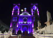 People walk past an illuminated St. Joseph Cathedral on the eve of the Christmas, in Hyderabad, India, Friday, Dec. 24, 2021. (AP Photo/Mahesh Kumar A.)