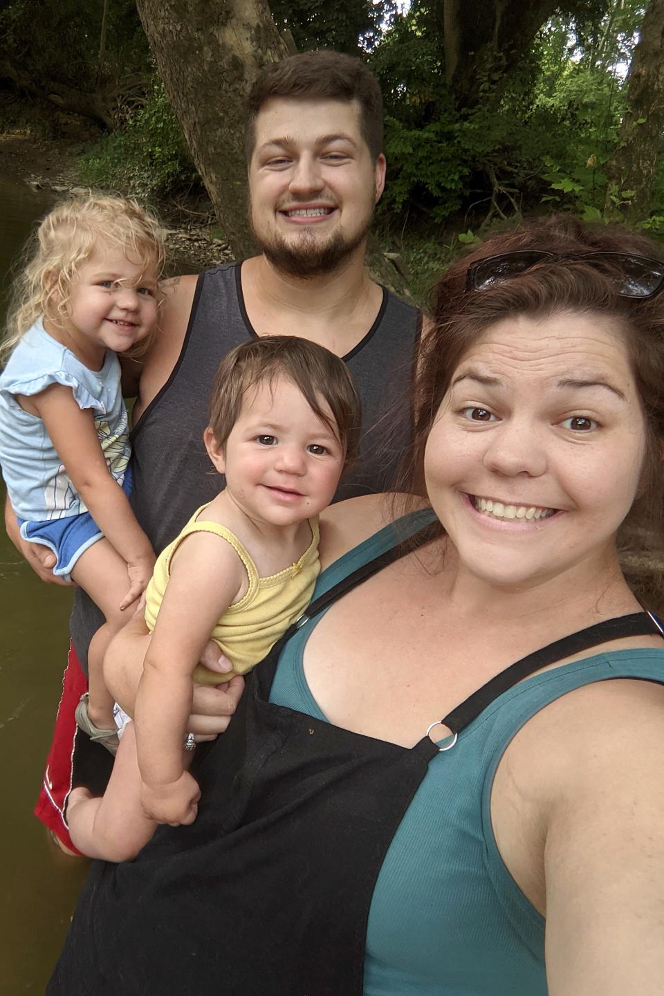 The Wiley family of Goshen Township smiles for a photo before Aislynn got sick with the rare disease Tango 2. Adelaide, 3, is in the arms of her father, Jacob Wiley. Aislynn is with her mother, Ashley Wiley.