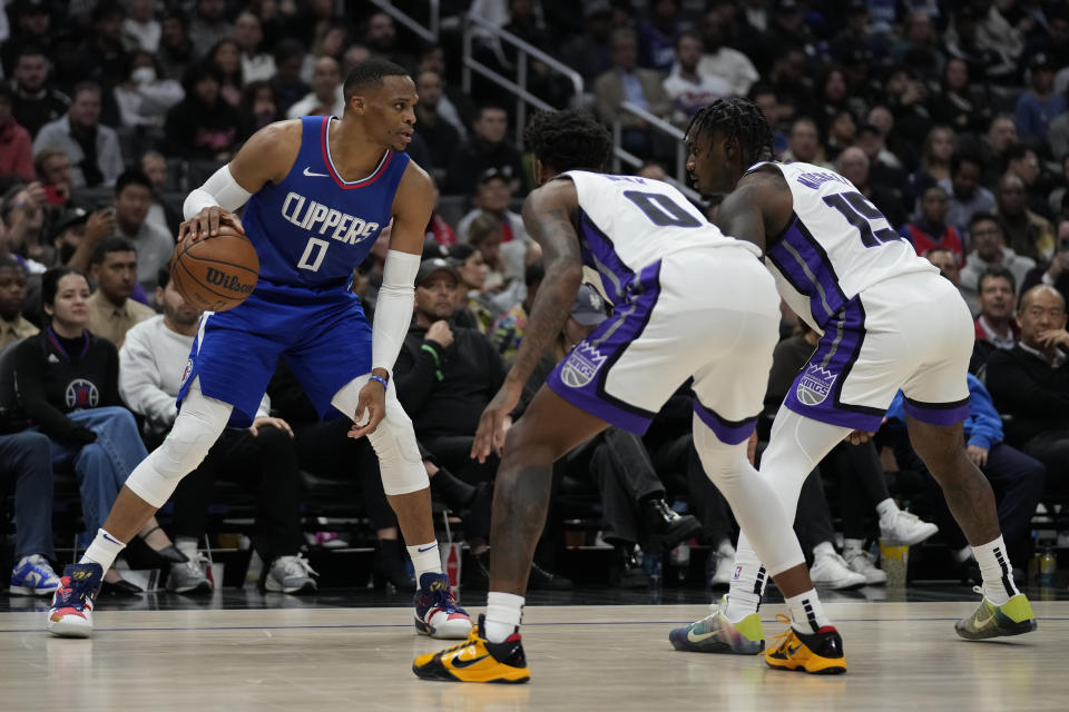 Los Angeles Clippers guard Russell Westbrook (0) is defended by Sacramento Kings guard Malik Monk (0) and guard Davion Mitchell (15) during the second half of an NBA basketball game in Los Angeles, Tuesday, Dec. 12, 2023. (AP Photo/Ashley Landis)