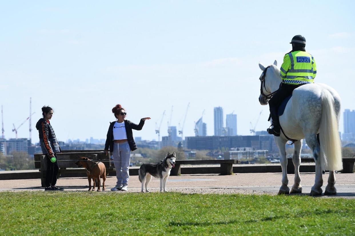 <p>Mounted police officers speak to people on Primrose Hill, London</p> (PA)