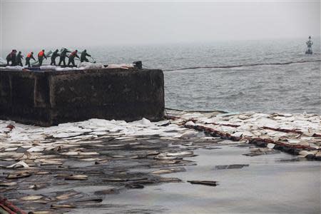 Workers set up oil fences to control leaked oil after Friday's explosion at a Sinopec Corp oil pipeline in Huangdao, Qingdao, Shandong Province November 24, 2013. REUTERS/Aly Song