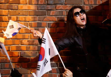 A supporter of South Korea's ousted leader Park Geun-hye waves the national flag as she waits for her arrival outside her private home in Seoul, South Korea, March 12, 2017. REUTERS/Kim Kyung-Hoon