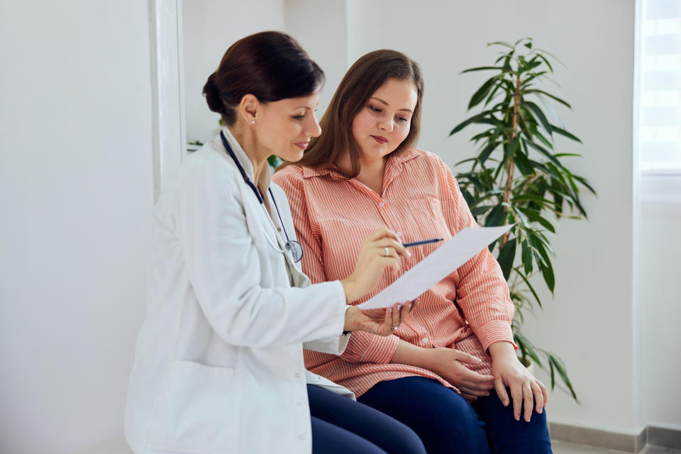 A smiling female nutritionist explaining a diet plan, a balanced and healthy menu for a pretty overweight woman.