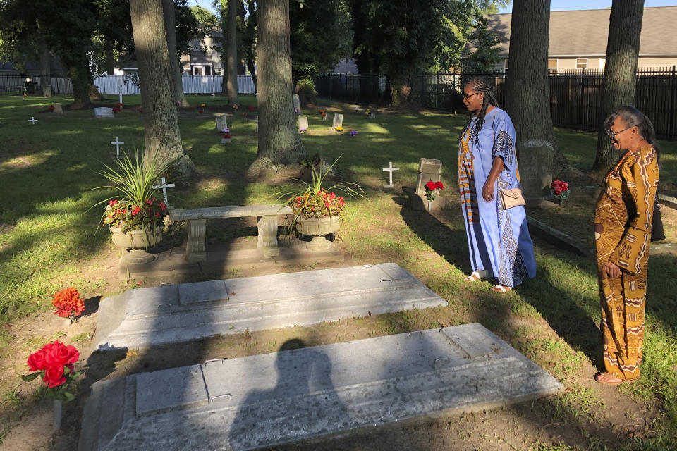 Earline Jackson, right, and Phyllis Bradshaw stand at a relative's grave in the Tucker Family Cemetery in Hampton, Va. on Friday, Aug. 23, 2019. They are part of a larger family that traces its roots to first enslaved Africans to arrive in Virginia in 1619. (AP Photo/Ben Finley)