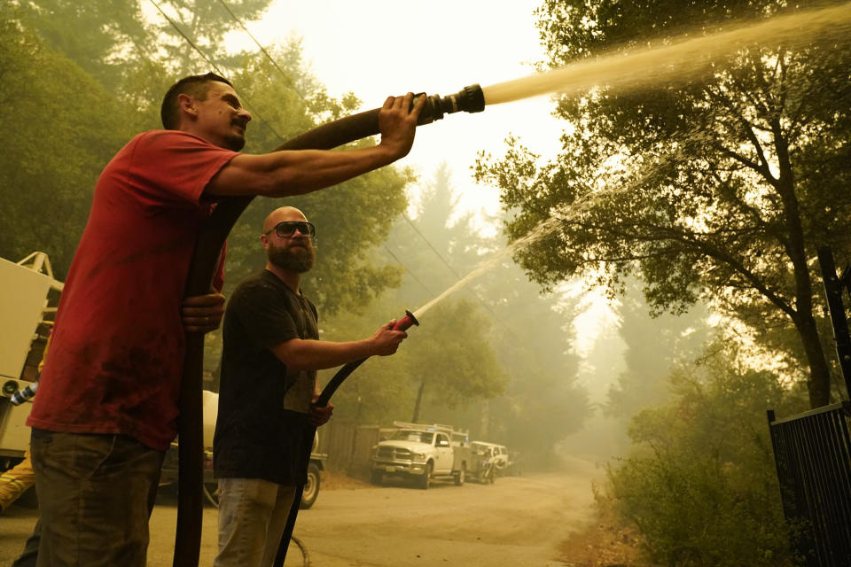 FILE - In this Aug. 20, 2020, file photo, civilian volunteers Brian Alvarez, left, and Nate Bramwell fight the CZU Lightning Complex Fire in Bonny Doon, Calif. With California fire crews strapped for resources as hundreds of lightning-sparked fires broke out in one night, crews of organized residents have worked to put out spot fires themselves in a massive complex of blazes along the central coast, banding together to sneak behind evacuation lines and keep properties safe. (AP Photo/Marcio Jose Sanchez, File)