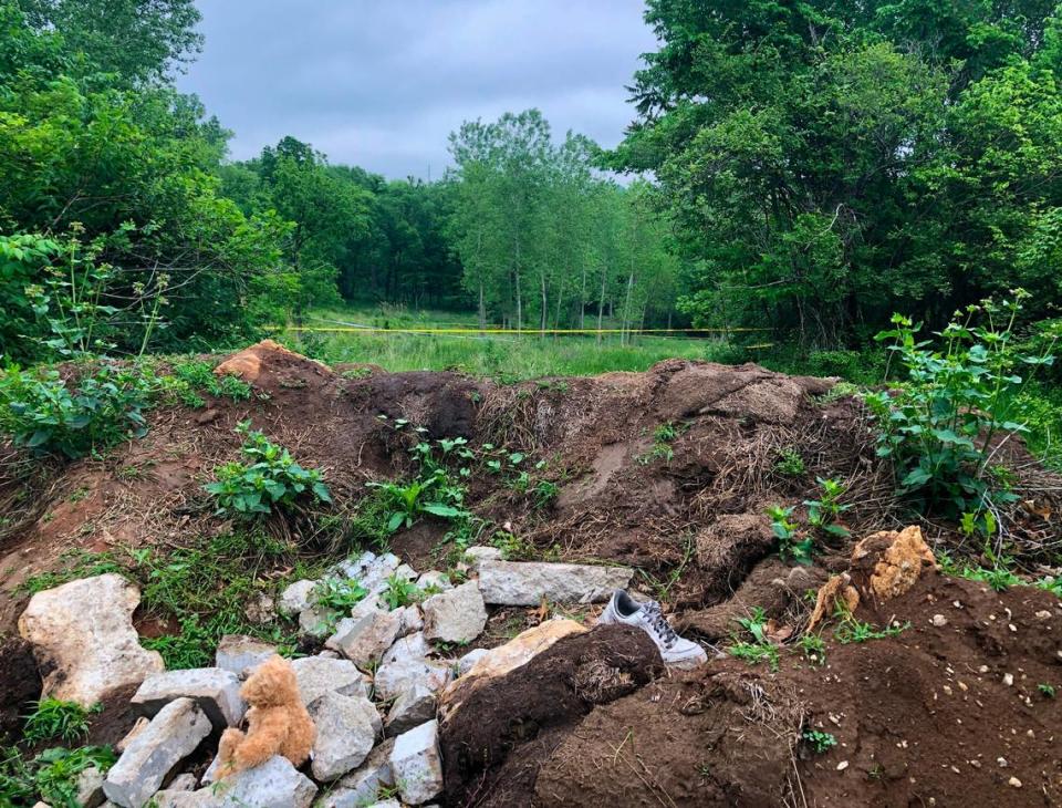 A teddy bear sits on a pile of rocks off Pittman Road, close to East 41st Street, near the entrance to a field where a small baby was found dead Saturday, May 13, 2023, Kansas City police said. Crime scene tape remained up two days later.
