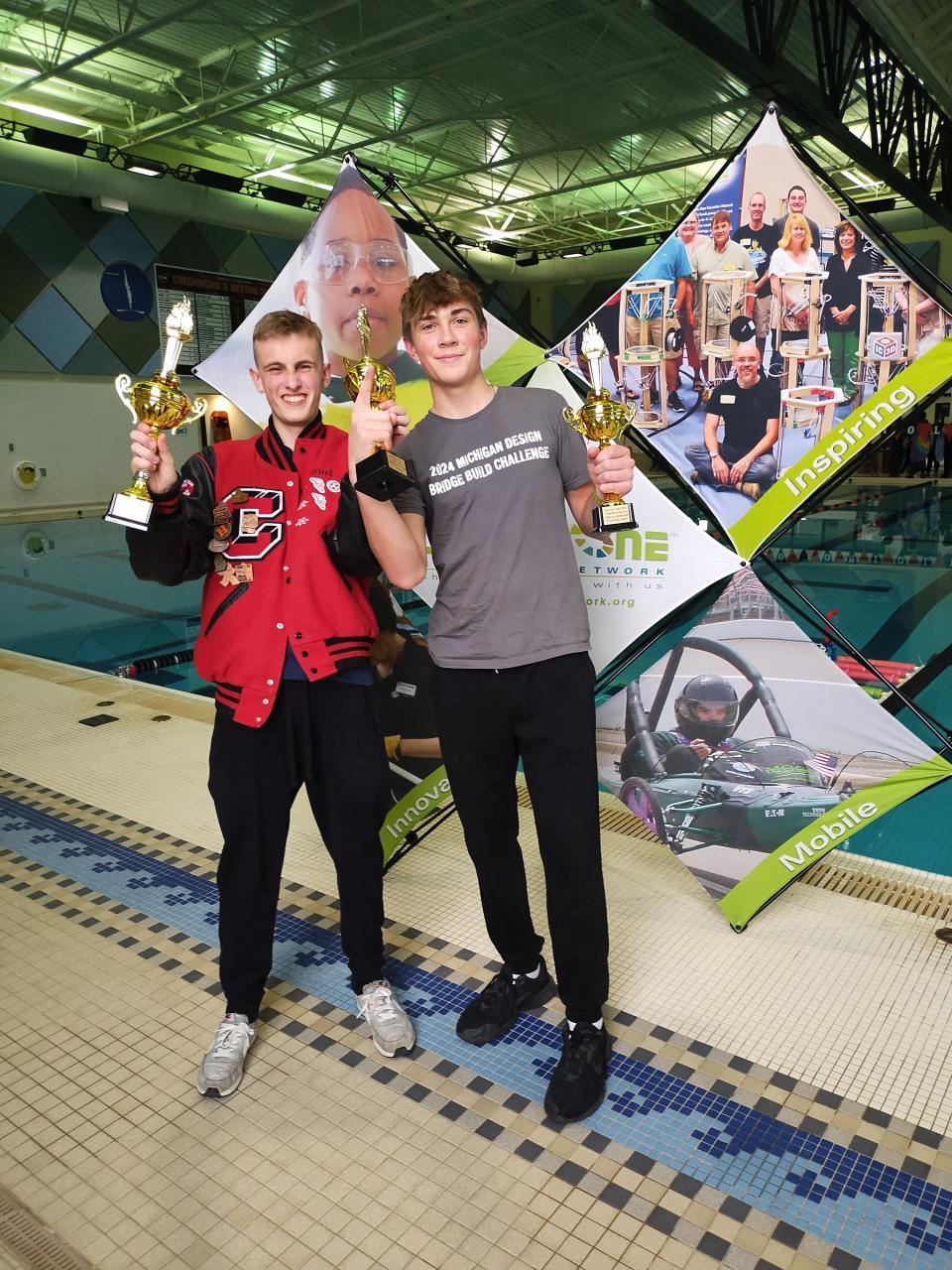 Gabe Manchester, left, and Jaren Settles, right, students at Clinton High School are seen March 20, 2024, celebrating and holding up their trophies after winning first place in the Ambassador Project, first place in the Perfect Pitch competition and first place for Overall Performance in the Senior Division during an underwater robotics competition hosted at the Charlotte Aquatic Center.