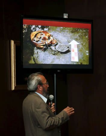 Raul Barrera, an archaeologist from the National Institute of Anthropology and History (INAH), speaks to the media as a picture of a skull that was discovered at the ruins of the Templo Mayor Aztec complex is seen above him, during a news conference at the Anthropology Museum in Mexico City August 20, 2015. REUTERS/Henry Romero