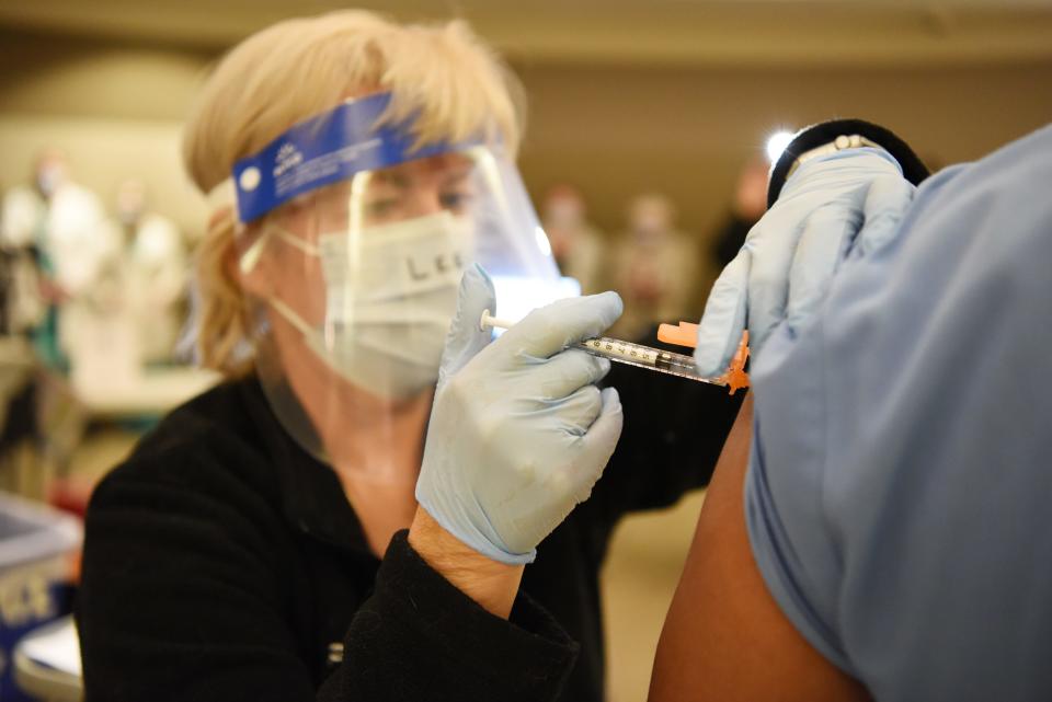 Registered nurse Lee Ellen Paulin administers the first dose of the COVID-19 vaccine to employees at St. Joseph's University Medical Center in Paterson, N.J., on Dec. 18.