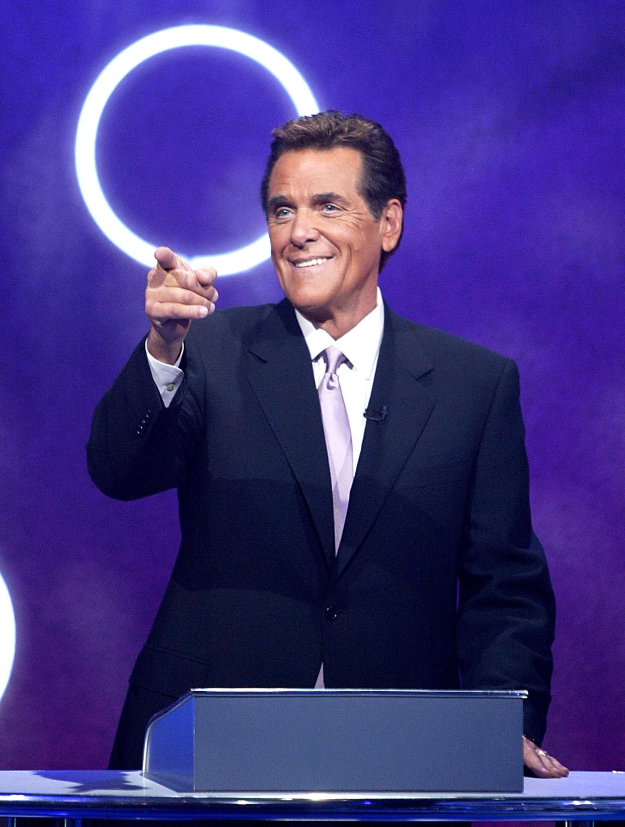 LOS ANGELES, CA - OCTOBER 17:  Host Chuck Woolery talks to a Playboy Playmate who were contestants on the gameshow "Lingo" October 17, 2003 in Los Angeles, California. "Lingo" is the highest original program on the Game Show Network.  (Photo by Carlo Allegri/Getty Images for Game Show Network)