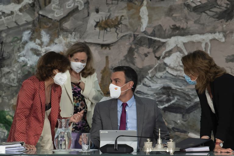 En esta foto provista por el gobierno español en Madrid, el presidente del gobierno, Pedro Sánchez, centro, conversa con tres ministras durante una reunión del consejo de ministros en el Palacio de la Moncloa, Madrid, martes 22 de junio de 2021