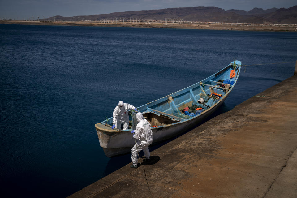 Police officers inspect a boat where 15 Malians were found dead adrift in the Atlantic on Thursday, Aug. 20, 2020 in Gran Canaria island, Spain. The 15 lifeless men were spotted inside a boat on Aug. 19 by a Spanish plane 80 nautical miles (148 kilometers, 92 miles) from the island of Gran Canaria. (AP Photo/Emilio Morenatti)