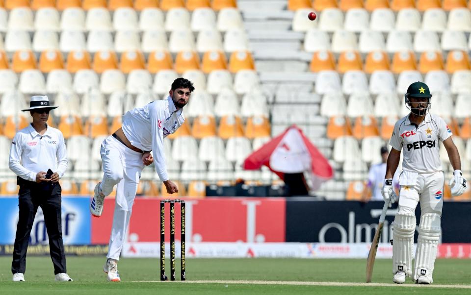 England's Shoaib Bashir (C) delivers a ball as Pakistan's Abdullah Shafique (R) looks on during the first day of the first Test cricket match between Pakistan and England, at the Multan Cricket Stadium in Multan on October 7, 2024.