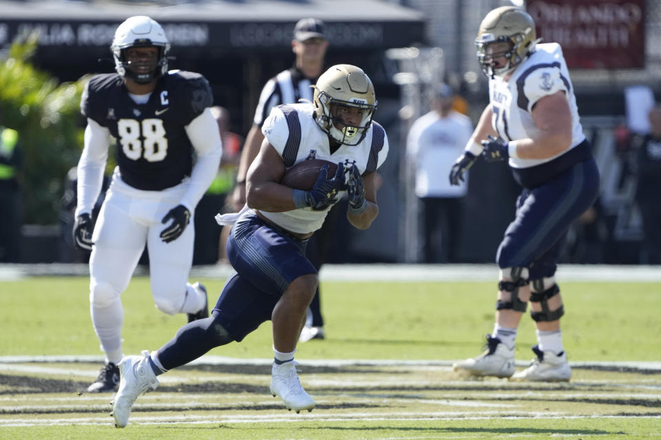 Navy fullback Daba Fofana, center, runs past Central Florida defensive end Josh Celiscar (88) for a 45-yard run during the first half of an NCAA college football game, Saturday, Nov. 19, 2022, in Orlando, Fla. (AP Photo/John Raoux)