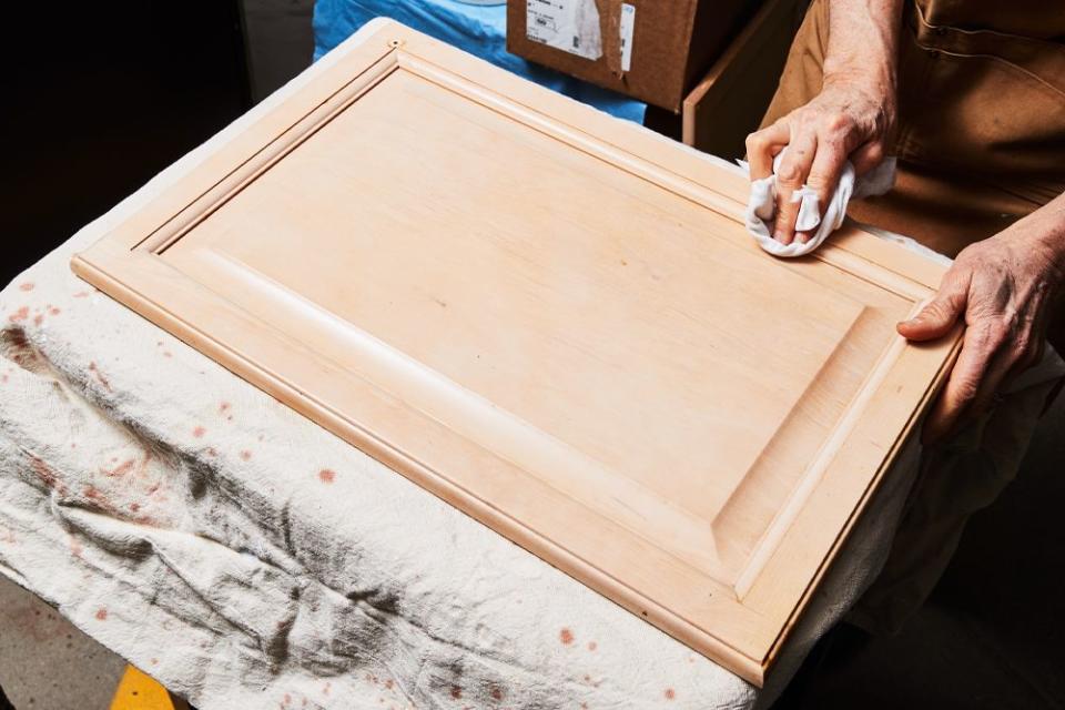 a person wiping down a removed piece of a kitchen cabinet