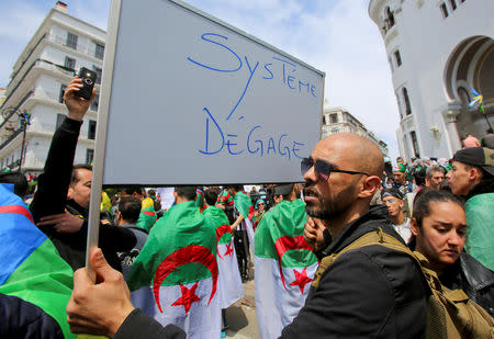 A man carries a sign reading "System, get out" during a protest seeking the departure of the ruling elite in Algiers, Algeria April 12, 2019. REUTERS/Ramzi Boudina