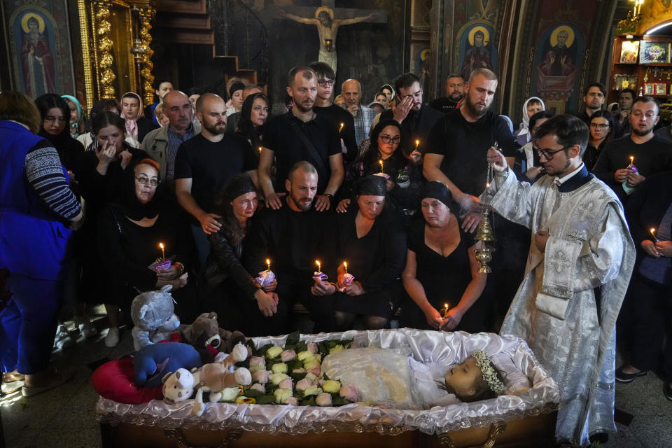 Relatives and friends pay their last respects to Liza, a 4-year-old girl killed by a Russian attack, during a mourning ceremony in an Orthodox church in Vinnytsia, Ukraine, Sunday, July 17, 2022. Wearing a blue denim jacket with flowers, Liza was among 23 people killed, including 2 boys aged 7 and 8, in Thursday's missile strike in Vinnytsia. Her mother, Iryna Dmytrieva, was among the scores injured. (AP Photo/Efrem Lukatsky)