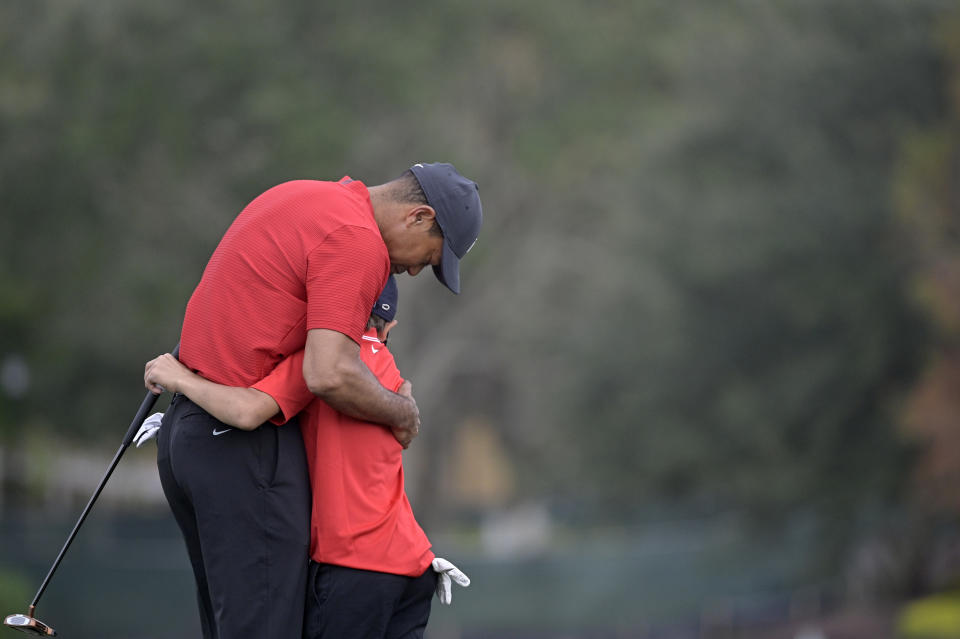 Tiger Woods hugs his son Charlie after finishing on the 18th green during the final round of the PNC Championship golf tournament, Sunday, Dec. 20, 2020, in Orlando, Fla. (AP Photo/Phelan M. Ebenhack)