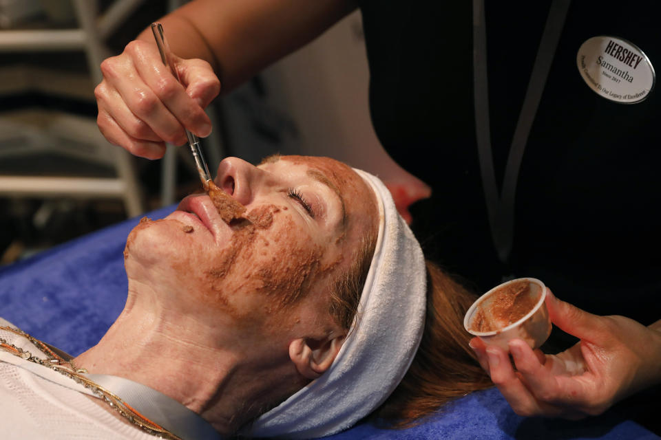 In this Tuesday, Aug. 6, 2019, photo, Hershey lead massage therapist Samantha Fisher applies a mini chocolate-and-marshmallow whip hydrating facial, at the 2019 International Spa Association event, in New York. It is Circadia's collaboration with MeltSpa by Hershey. (AP Photo/Richard Drew)