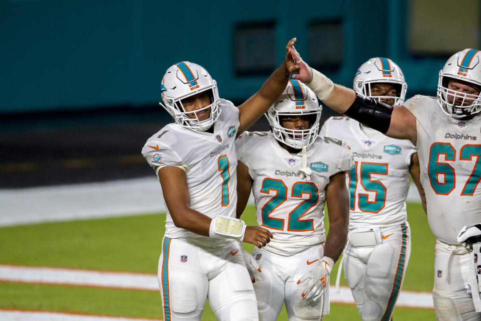 Miami Dolphins quarterback Tua Tagovailoa (1) celebrates his first NFL play with Miami Dolphins running back Matt Breida (22), Miami Dolphins guard Ted Karras (67) and Miami Dolphins running back Lynn Bowden (15) against the New York Jets during an NFL football game, Sunday, Oct. 18, 2020, in Miami Gardens, Fla. Tagovailoa’s winning personality helped the Miami Dolphins avoid locker room backlash when he was promoted to replace popular veteran Ryan Fitzpatrick. (AP Photo/Doug Murray)