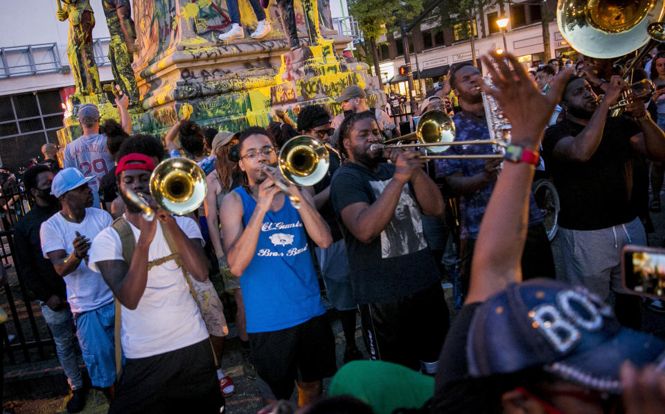 A band plays in front of the Confederate monument in Portsmouth, Va., during a demonstration on Wednesday, June 10, 2020. Protesters beheaded and then pulled down four statues that were part of a Confederate monument. The crowd was frustrated by the Portsmouth City Council’s decision to put off moving the monument. (Kristen Zeis/The Virginian-Pilot via AP)