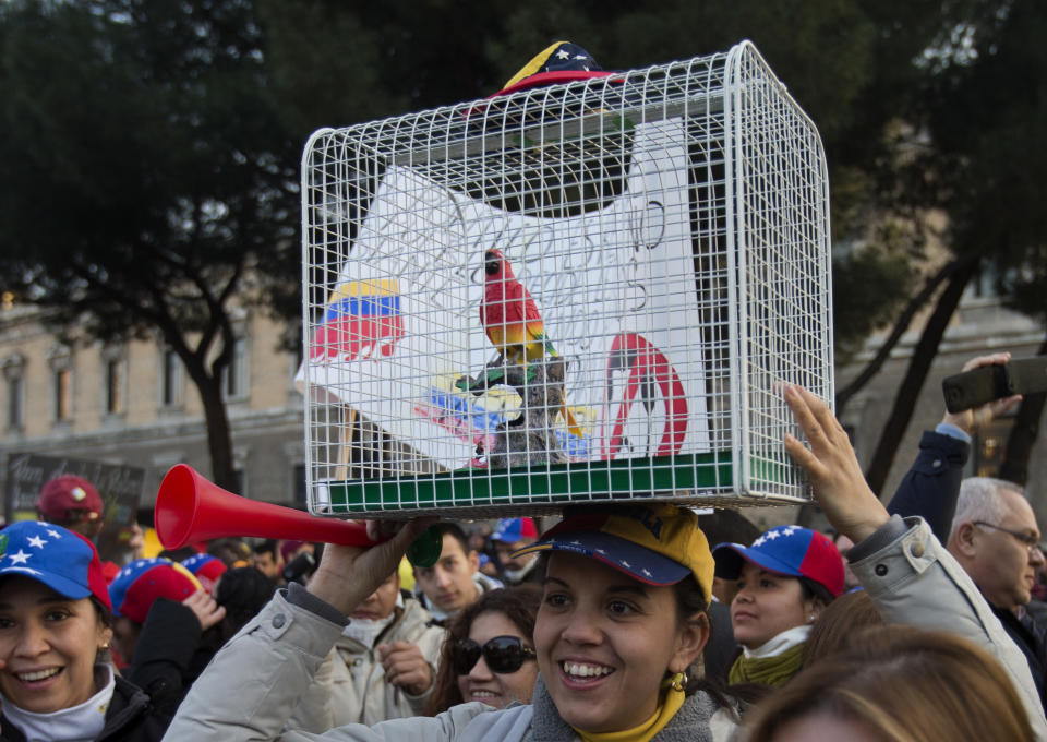 Venezolanos protestan contra el gobierno del presidente Nicolás Maduro y uno porta una jaula con un pajarito en Madrid, España, el martes 18 de febrero de 2014