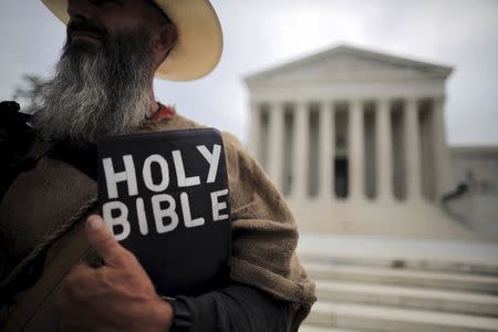 A protester holds a copy of the bible outside of the U.S. Supreme Court building in Washington June 15, 2015. REUTERS/Carlos Barria