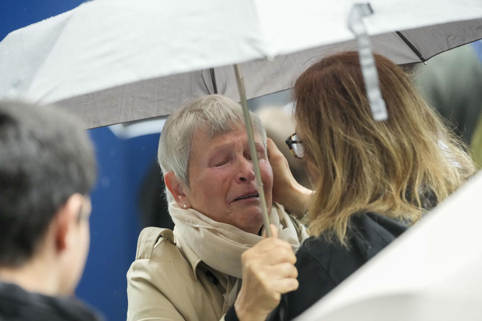 People cry in front of the Vladislav Ribnikar school during a memorial ceremony to mark the first anniversary of a shooting that killed 10 people in Belgrade, Serbia, Friday, May 3, 2024. (AP Photo/Darko Vojinovic)