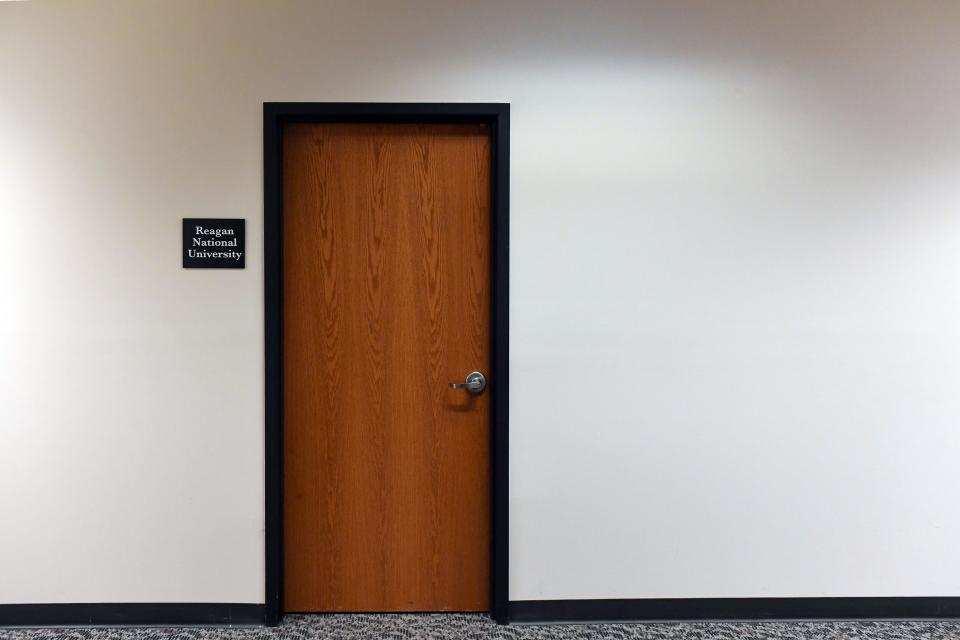 A sign for Reagan National University is posted outside one of two locked doors in a Sioux Falls office building in January 2020.