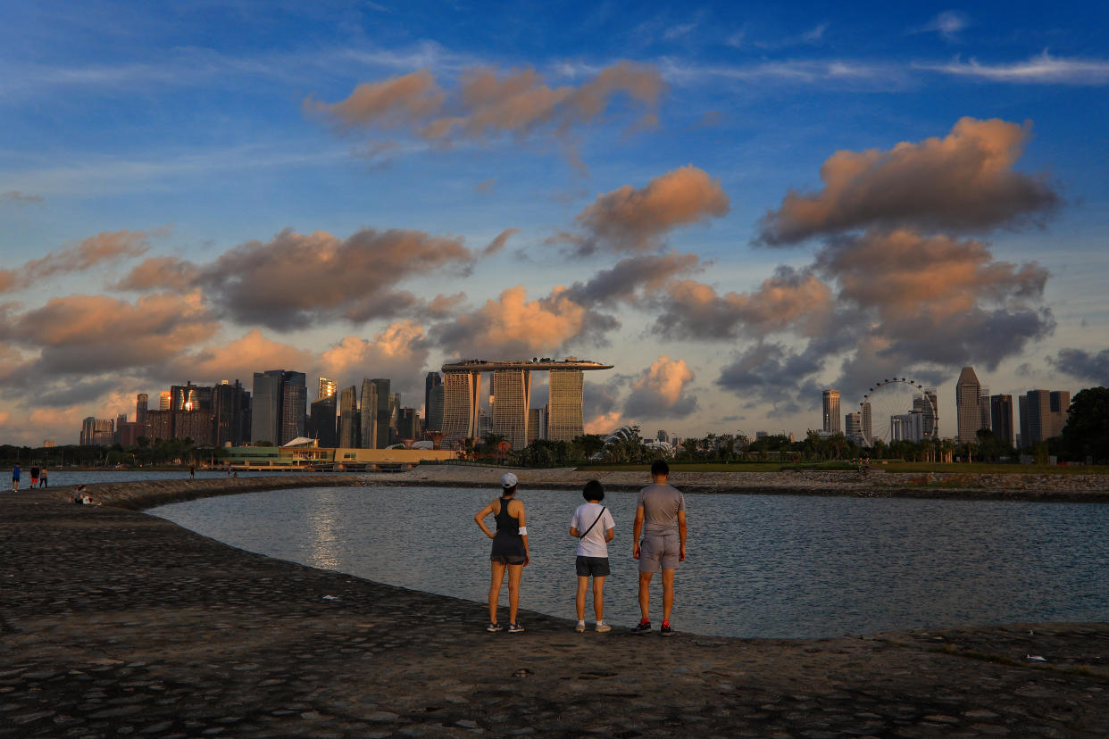 People look at the city skyline at sunrise on June 4, 2021 in Singapore. Singapore enters a month long heightened alert from May 16 to June 13 to curb the spread of COVID-19 cases in the local community. New restrictions on movements and activities have been introduced such as limiting social interaction to two, prohibiting dining out and a reduced operating capacity at shopping malls, offices and attractions. (Photo by Suhaimi Abdullah/NurPhoto via Getty Images)