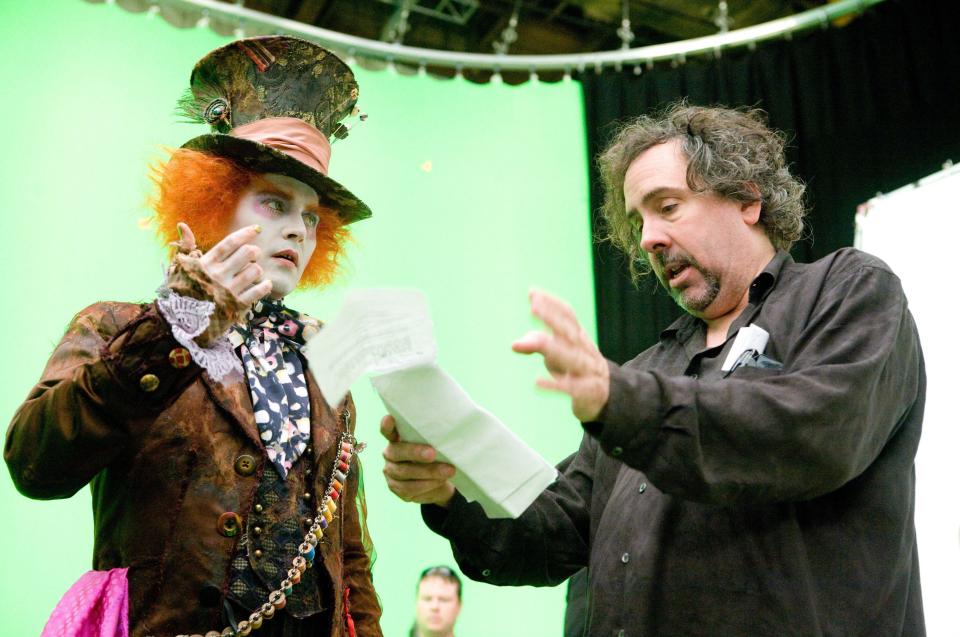 Johnny Depp, in character as the Mad Hatter, taking direction from director Tim Burton (right) on the set of 2010's Alice In Wonderland. (Disney/Alamy)