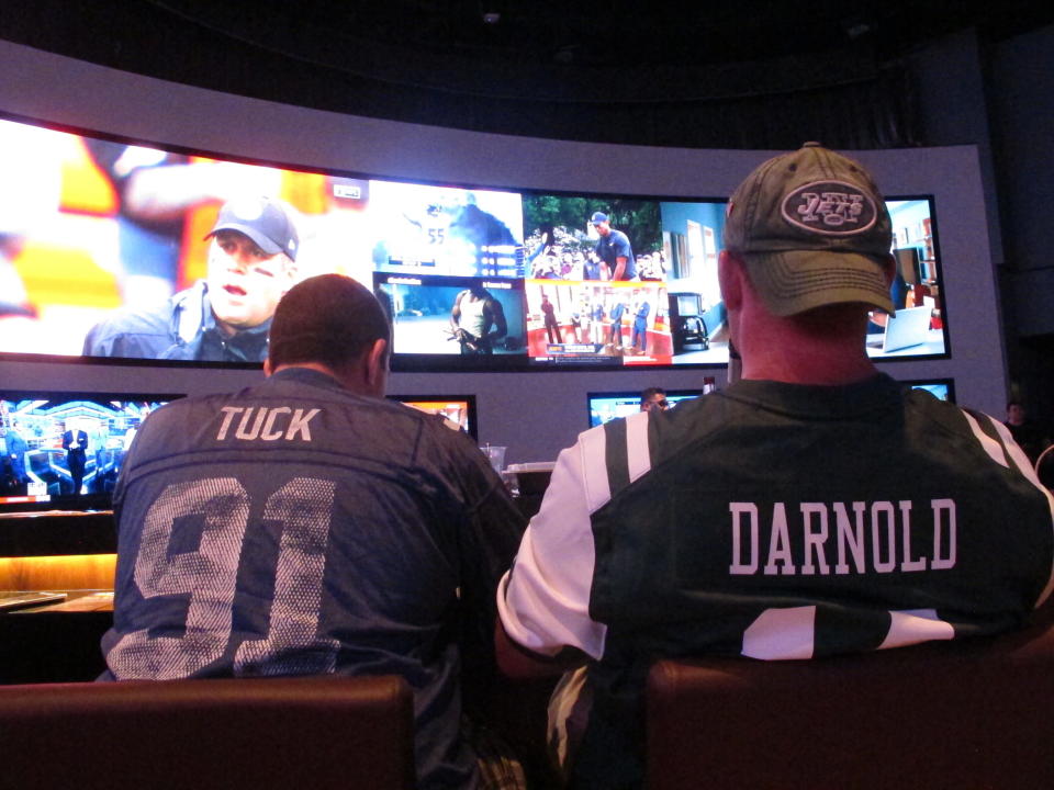 FILE: This Sept. 9, 2018 file photo shows football fans waiting for kickoff in the sports betting lounge at the Ocean Casino Resort in Atlantic City, N.J. A report released Feb. 2, 2021 by the American Gaming Association predicts fewer Americans will bet on this year's Super Bowl, a decrease driven largely by fewer people back at work in offices where betting pools are circulated. But the report also predicts a record amount will be wagered online this year. (AP Photo/Wayne Parry, FILE)