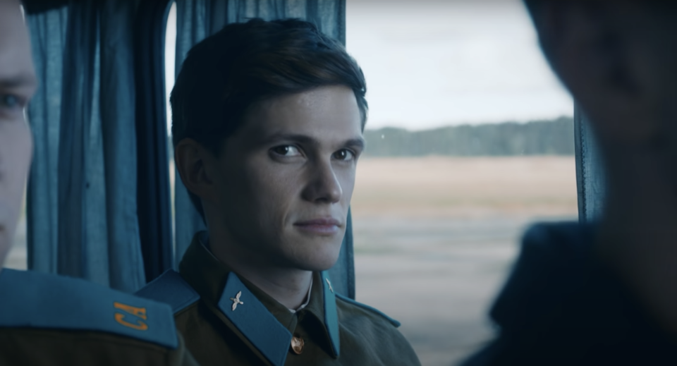 A man wearing a military uniform rides a train