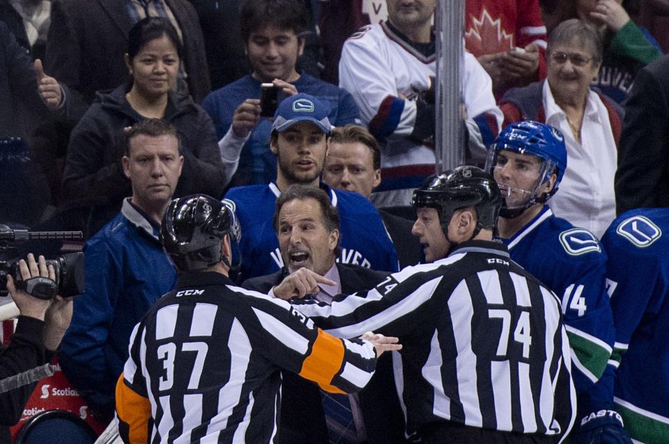 Referees get in the way of Vancouver Canucks head coach John Tortorella as he screams at the Calgary Flames bench during first period NHL hockey action at Rogers Arena in Vancouver, British Columbia Saturday Jan. 18, 2014. (AP Photo/The Canadian Press, Jonathan Hayward)