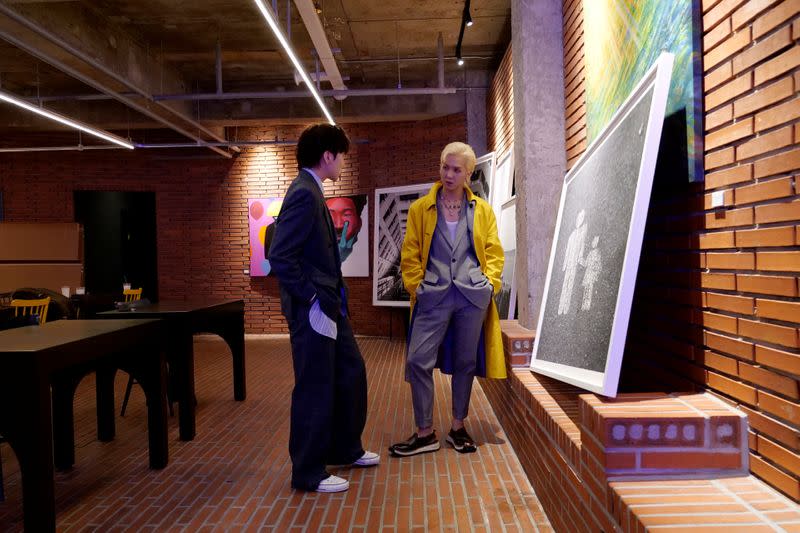 Foto de MINO y KANG SEUNG YOON frente a sus obras de arte en un café en Seúl.