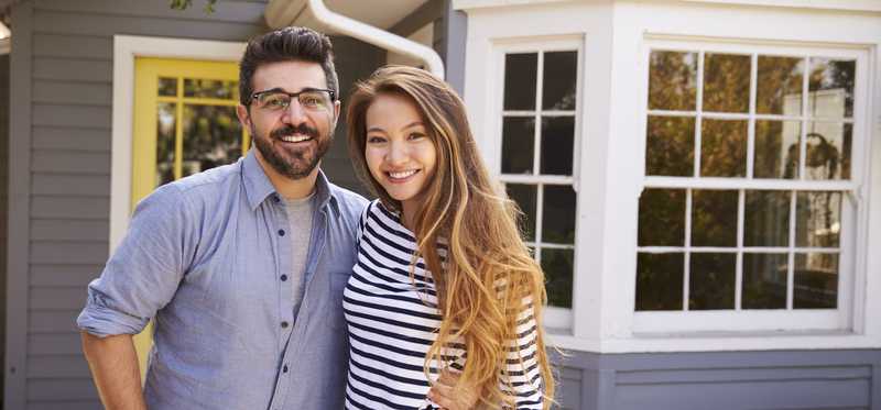 Young couple in front of a house.