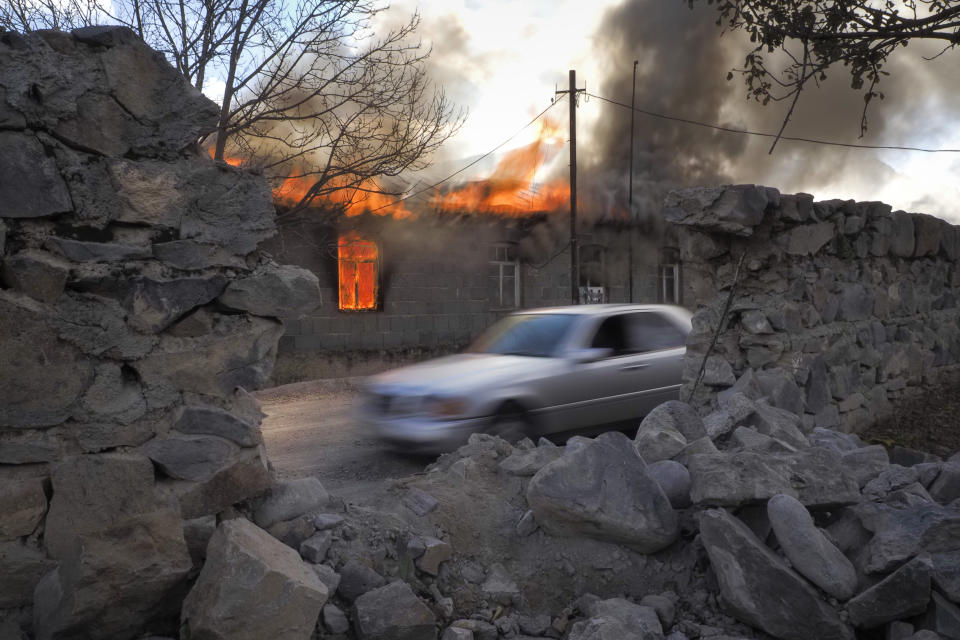 FILE - In this Friday, Nov. 13, 2020 file photo, smoke and flame rises from a burning house in an area once occupied by Armenian forces but soon to be turned over to Azerbaijan, in Karvachar, the separatist region of Nagorno-Karabakh. With Azerbaijan regaining control of land it lost to Armenian forces a quarter-century ago, civilians who fled the fighting decades ago are wondering if they can go back home now. But as Azerbaijani forces discovered when the first area was turned over Friday, Nov. 20 much of the recovered land is uninhabitable. (AP Photo/Dmitry Lovetsky, file)